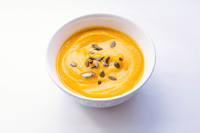 Butternut squash soup with pumpkin seeds on top on white backgro